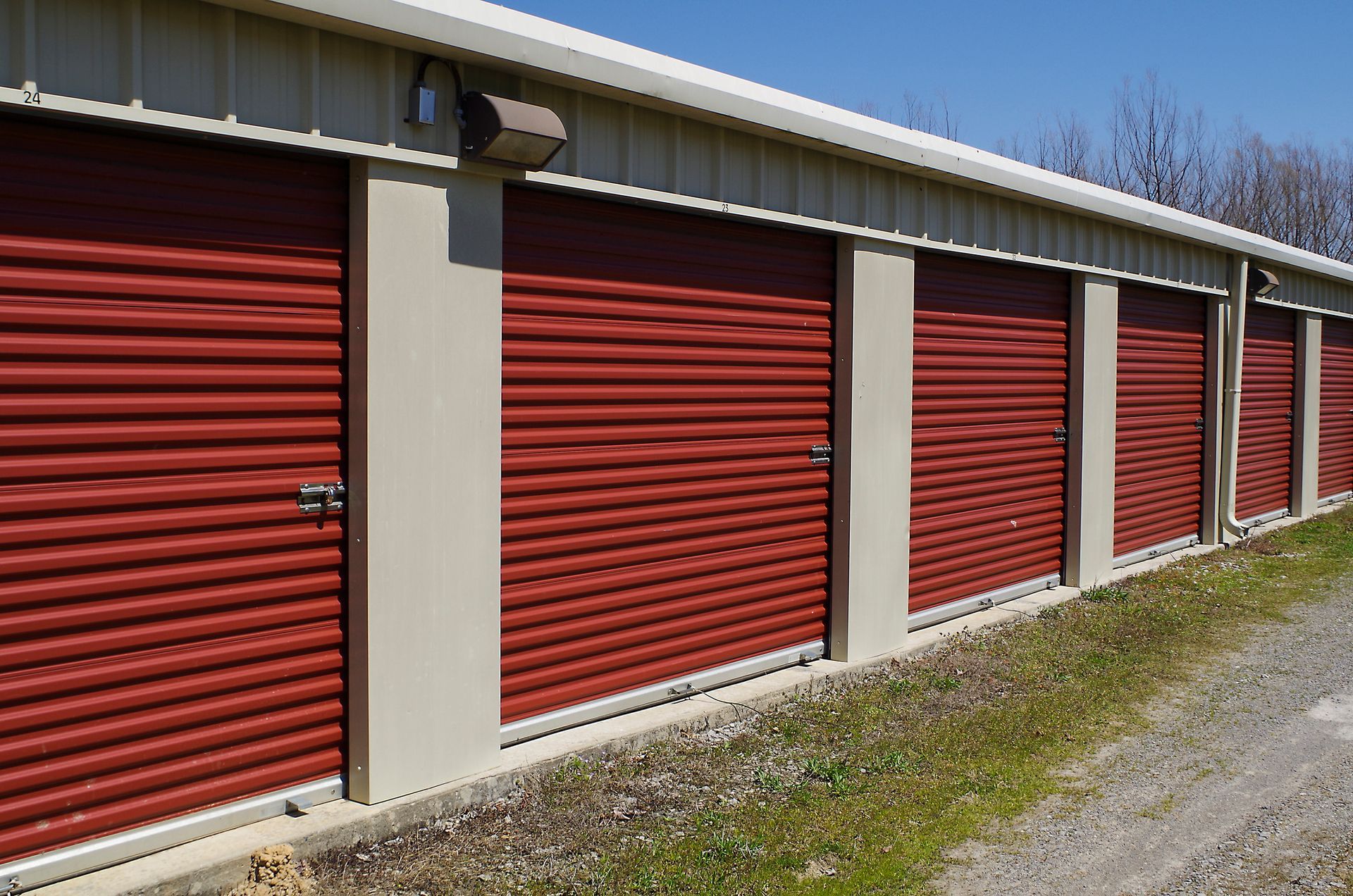 Red storage unit doors in a row, beige trim, on a sunny day.