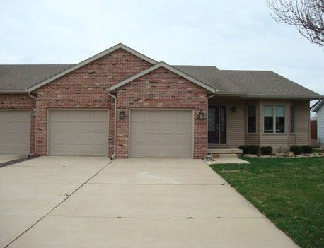 Brick townhomes with beige garage doors and a concrete driveway.