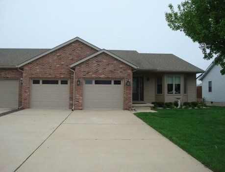 Brick house with beige garage doors and a concrete driveway.