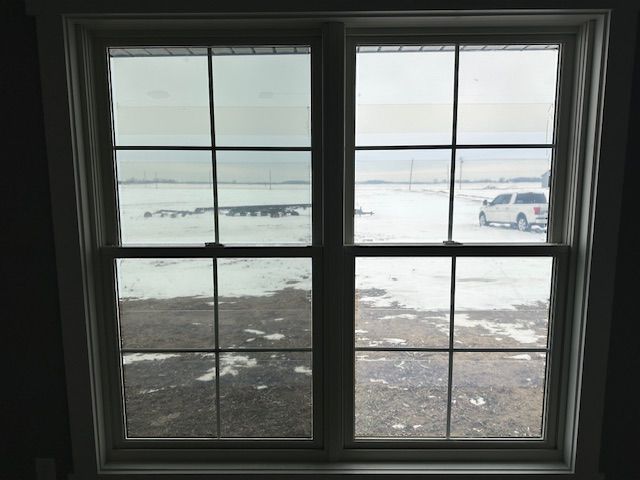 Two pane window, outside winter scene with snow. A vehicle is visible to the right.