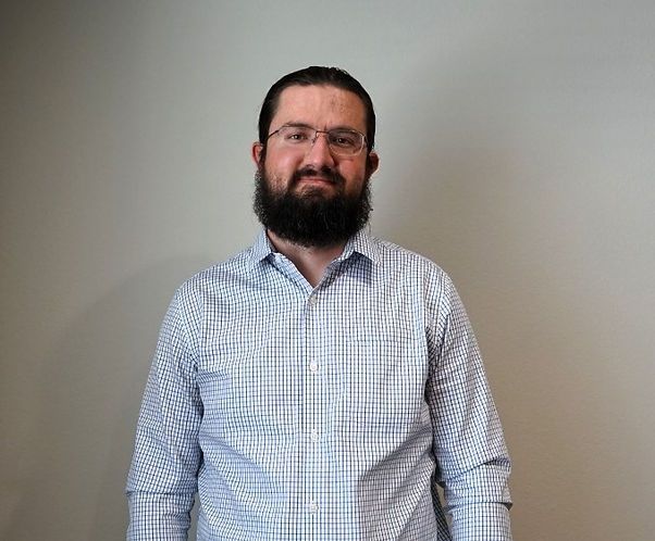 A man with a beard and glasses is wearing a plaid shirt.