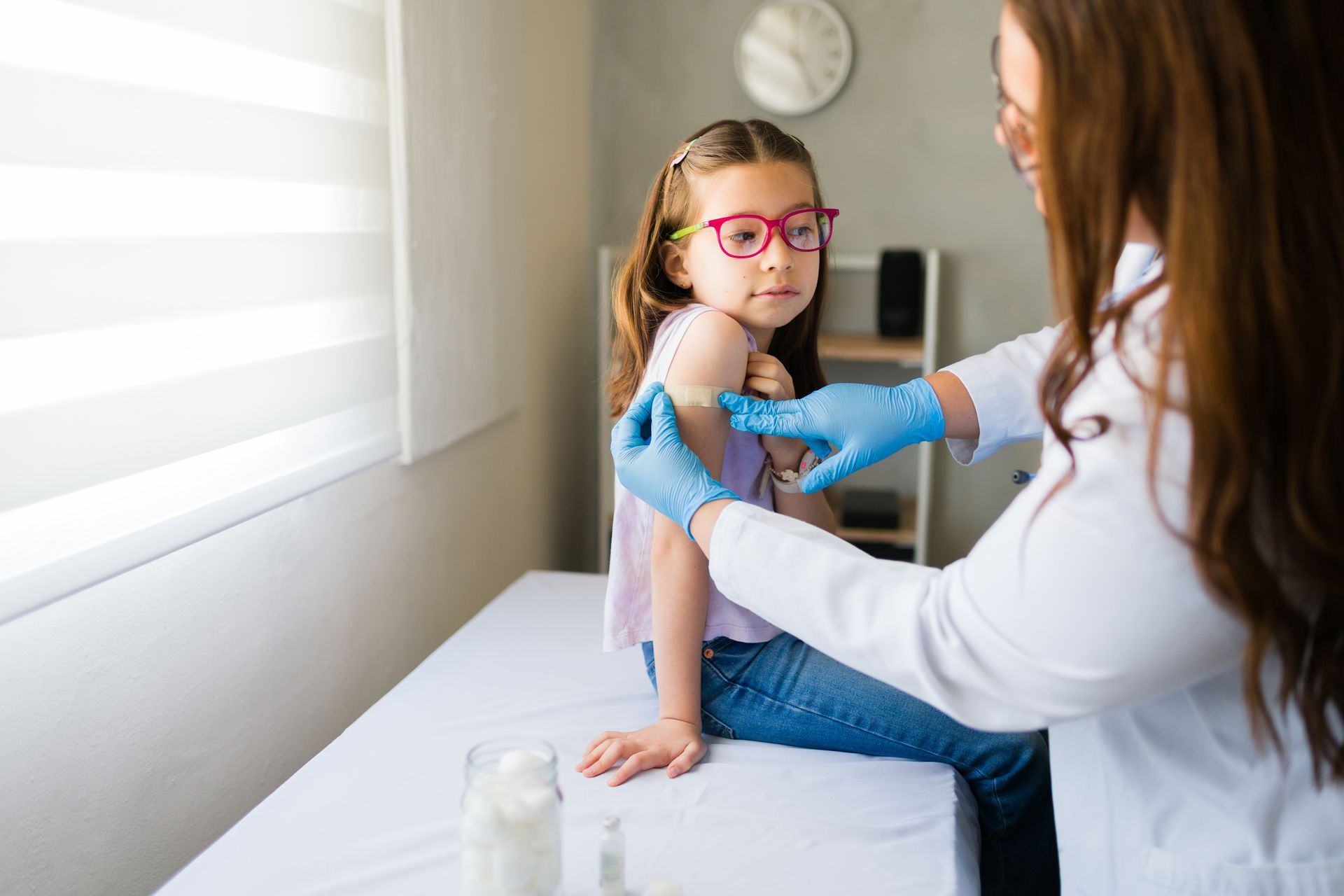 Medical professional applying a bandage after vaccination on a child’s upper arm.