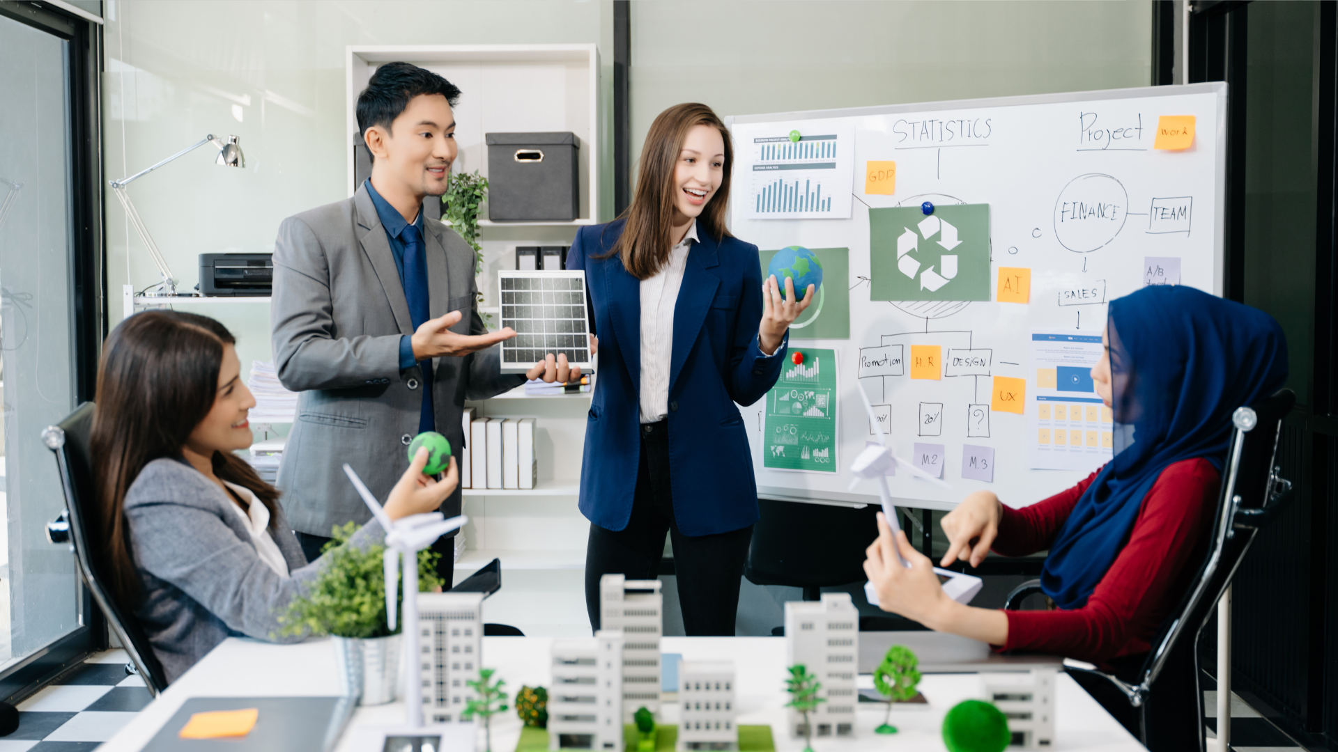 A diverse team in a professional office discusses a sustainable city model, with solar panels and a recycling whiteboard.