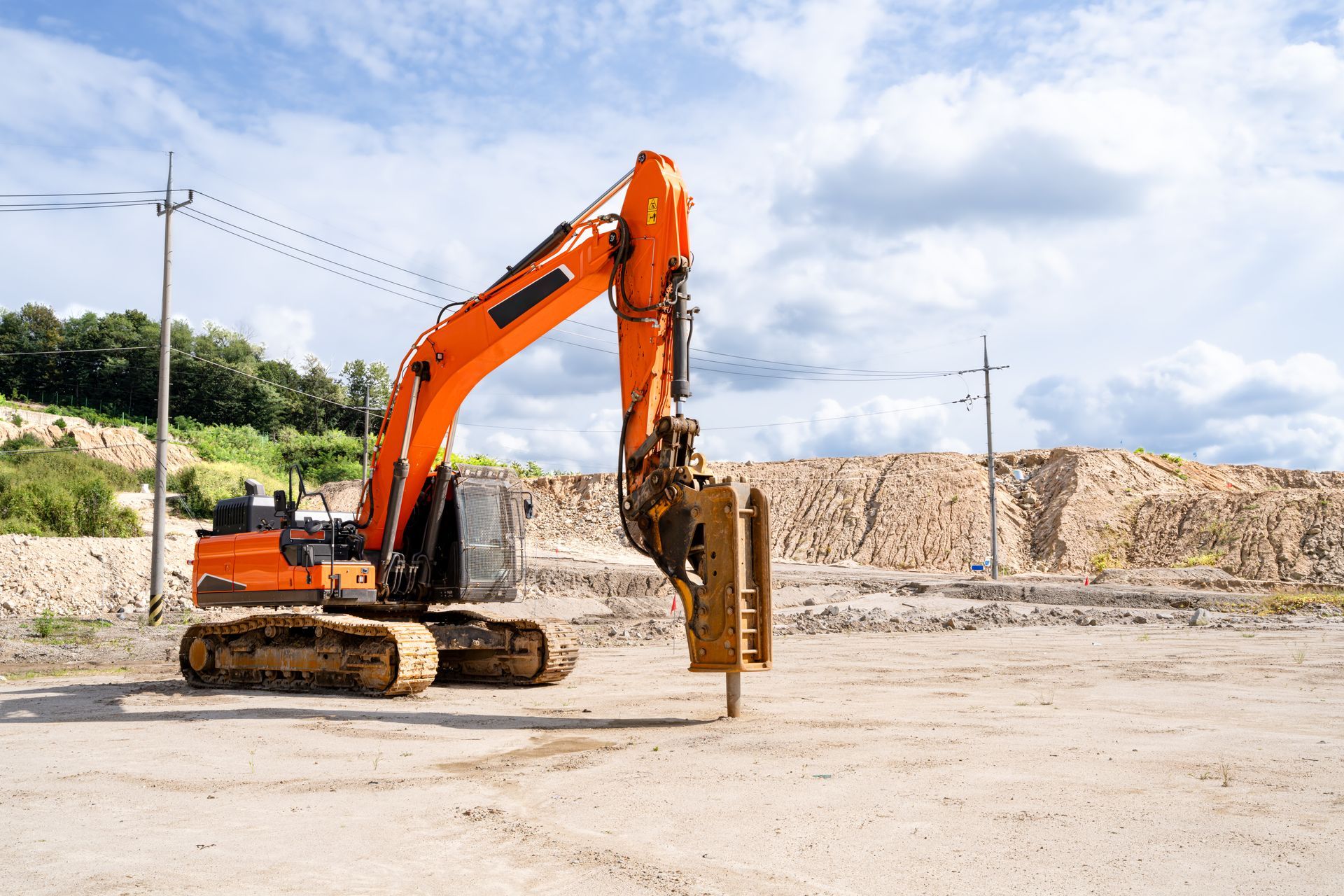 Orange excavator at a construction site, preparing the ground. Sunny day.