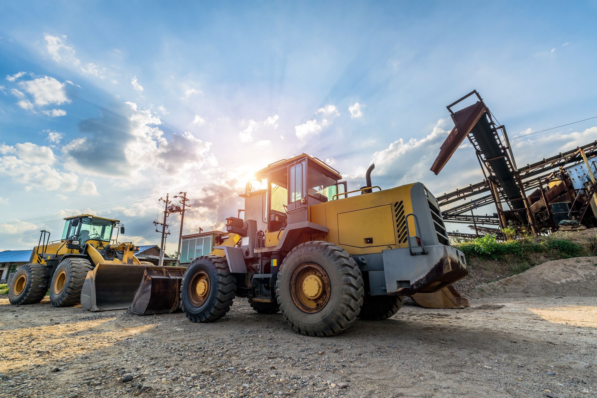Yellow construction loaders at a quarry under a bright, sunny sky.