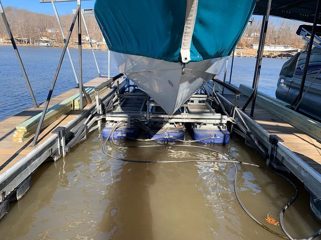 Boat in a lift, turquoise cover, brown water, dock structure.