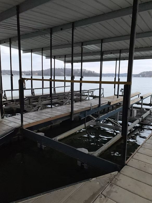 Boat dock with metal supports and roof over the water, water lapping at the docks.