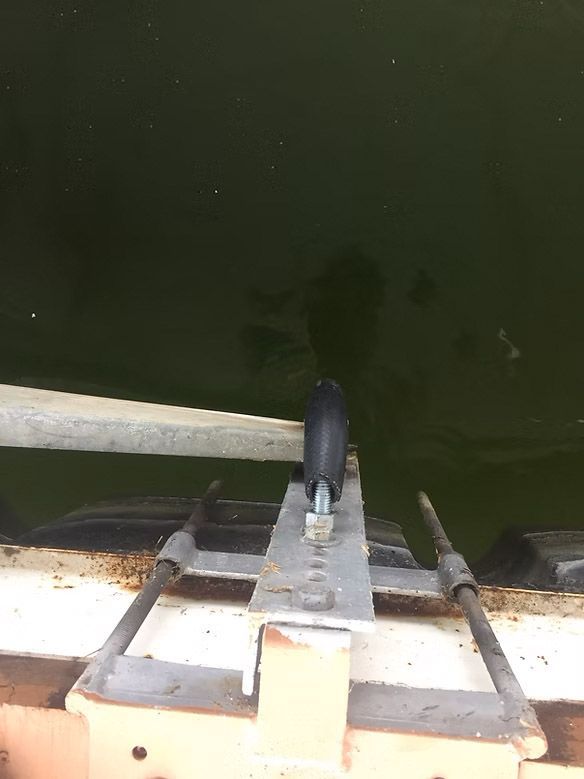 Metal boat lift with dark water. A black roller is mounted on the lift.