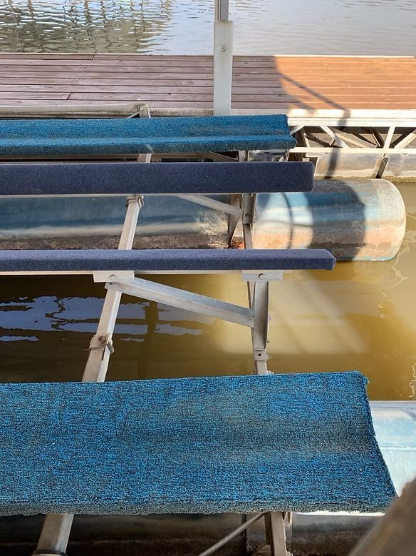 Dock with blue benches, metal frame, and water in the background. Wooden dock at the top.