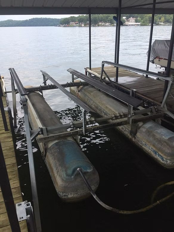 Boat lift on a dock with a lake in the background, under a covered structure.