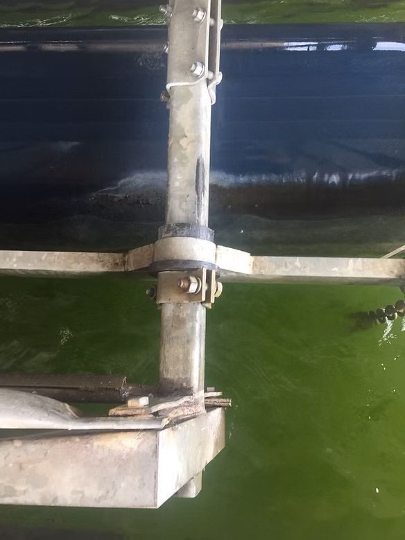 Metal structure in green water, possibly an industrial device.