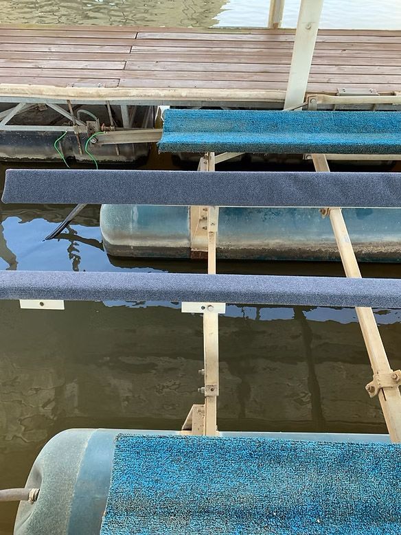 Rollers and docks on a lake. Blue, grey, and teal rollers mounted on metal supports. Wooden dock above.