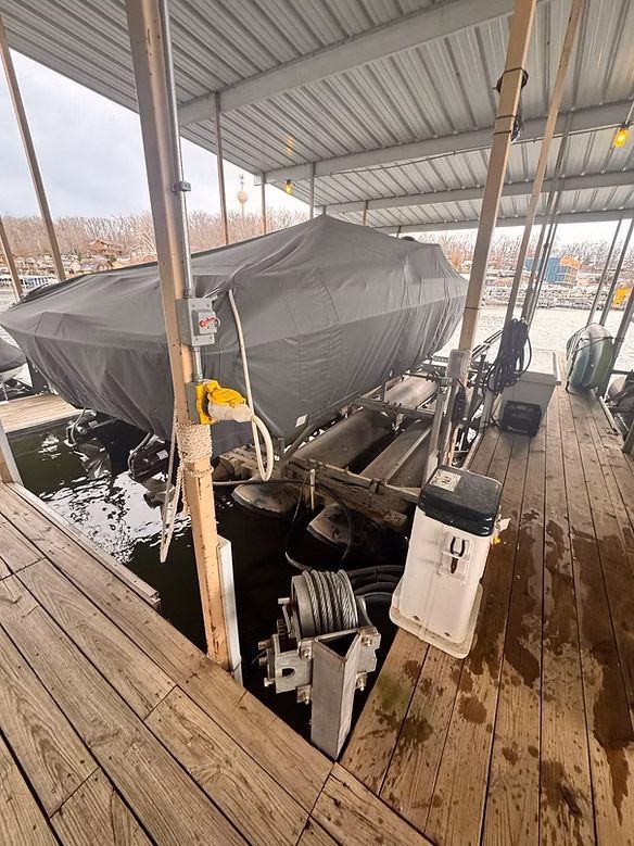 Boat covered by a gray tarp on a wooden dock at a marina.