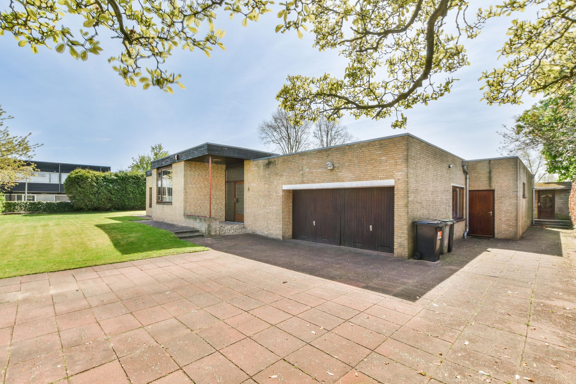 Modern house with a double garage, brick exterior, large windows, neat lawn