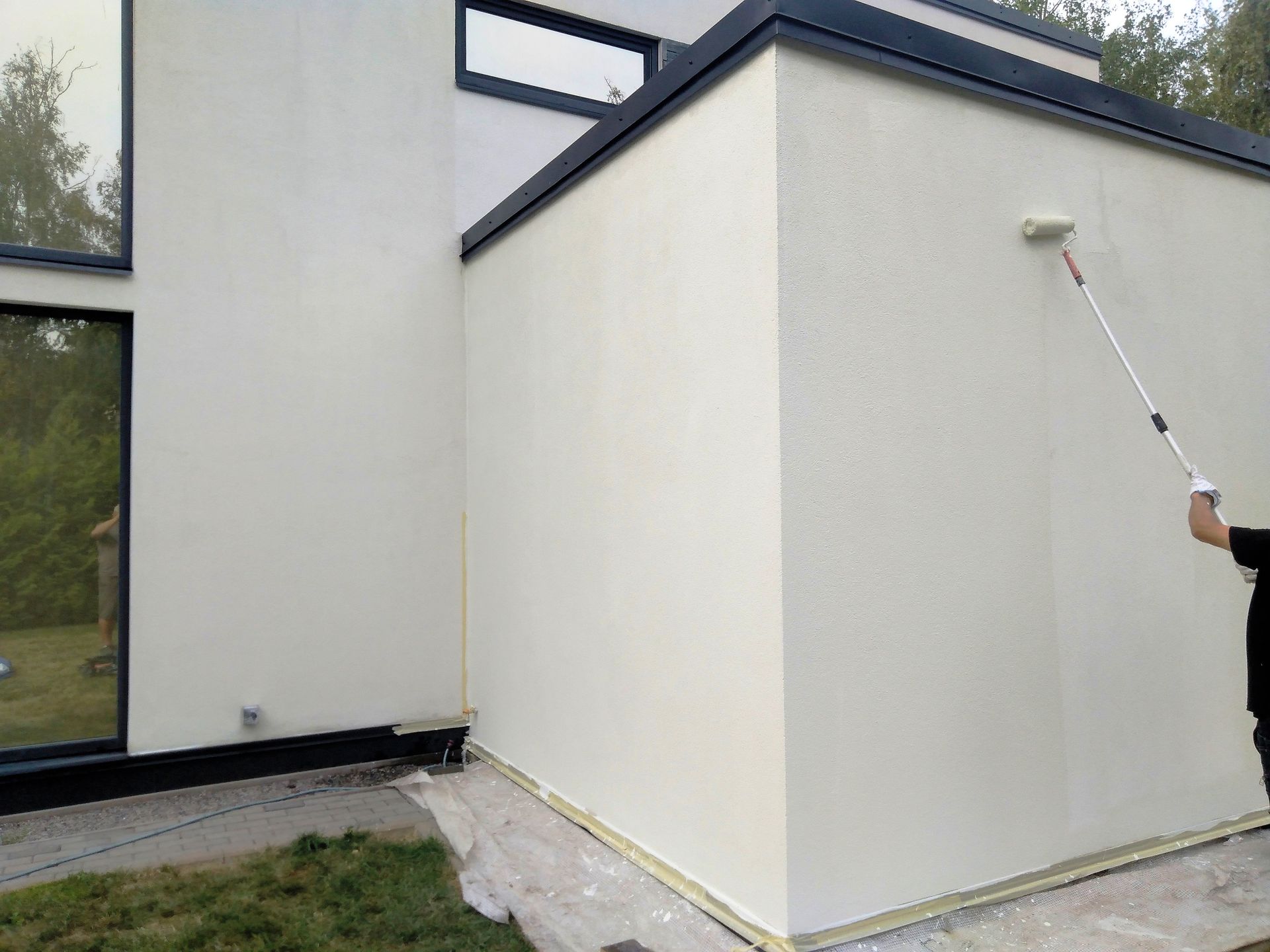 A man is painting a white wall with a roller.