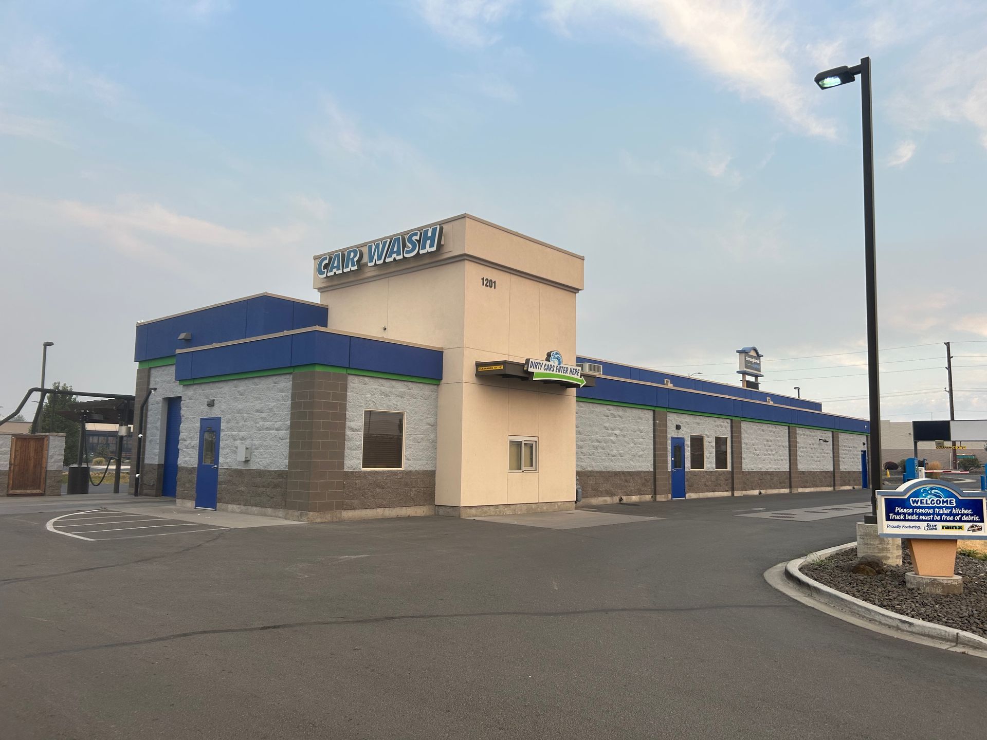 A large building with a blue roof is sitting on the side of a road.