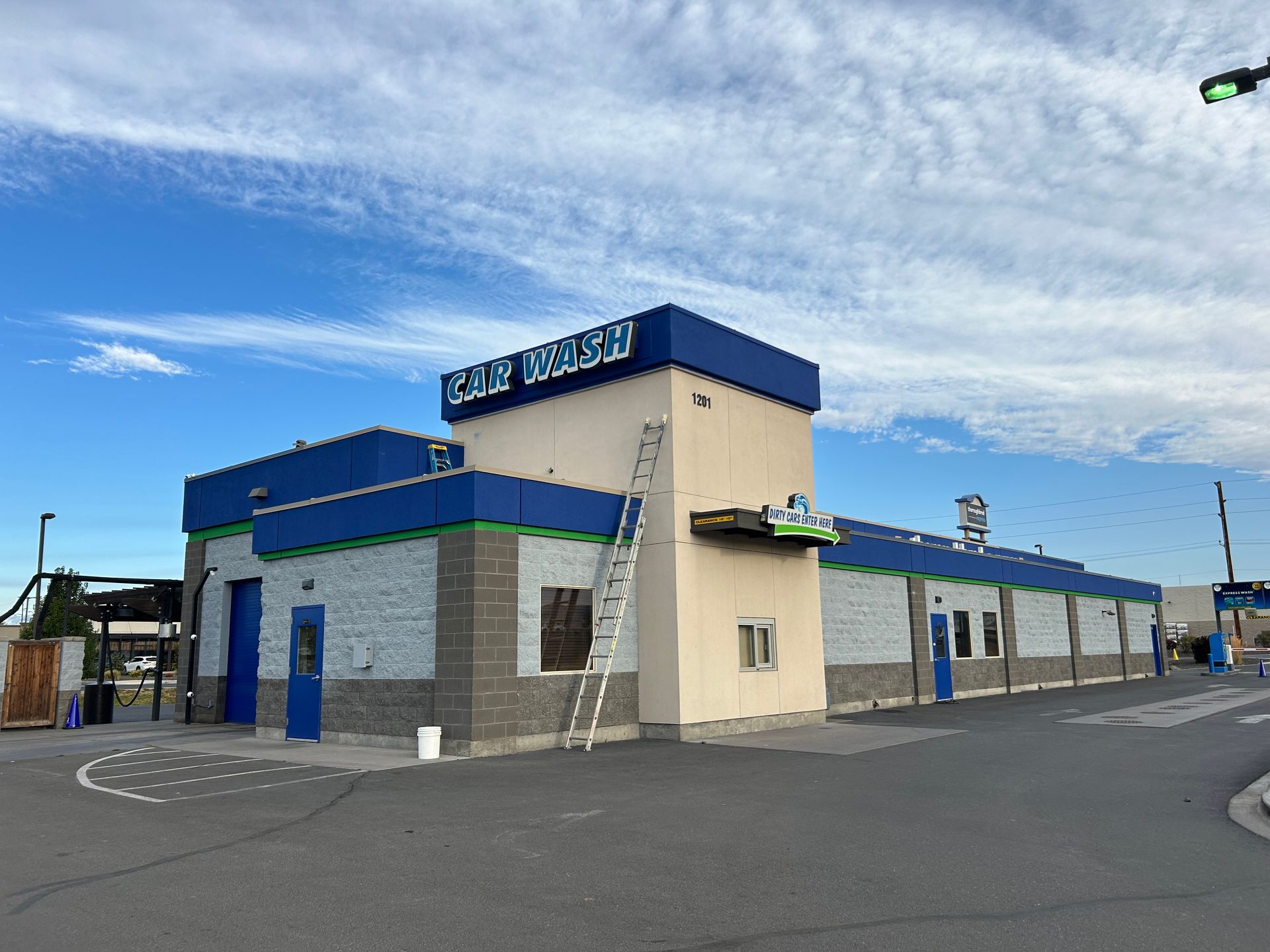 A large building with a blue roof is being painted.