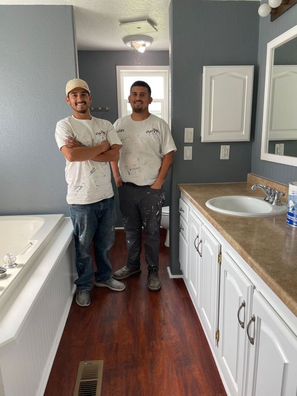 Two men are standing next to each other in a bathroom.