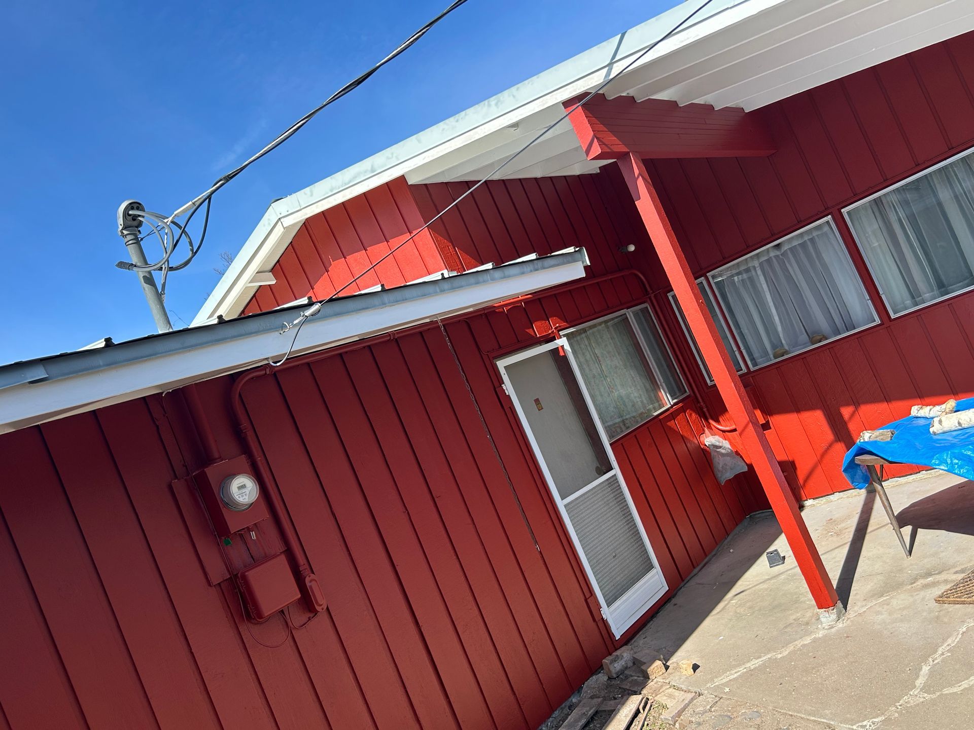 A red house with a blue tarp in front of it
