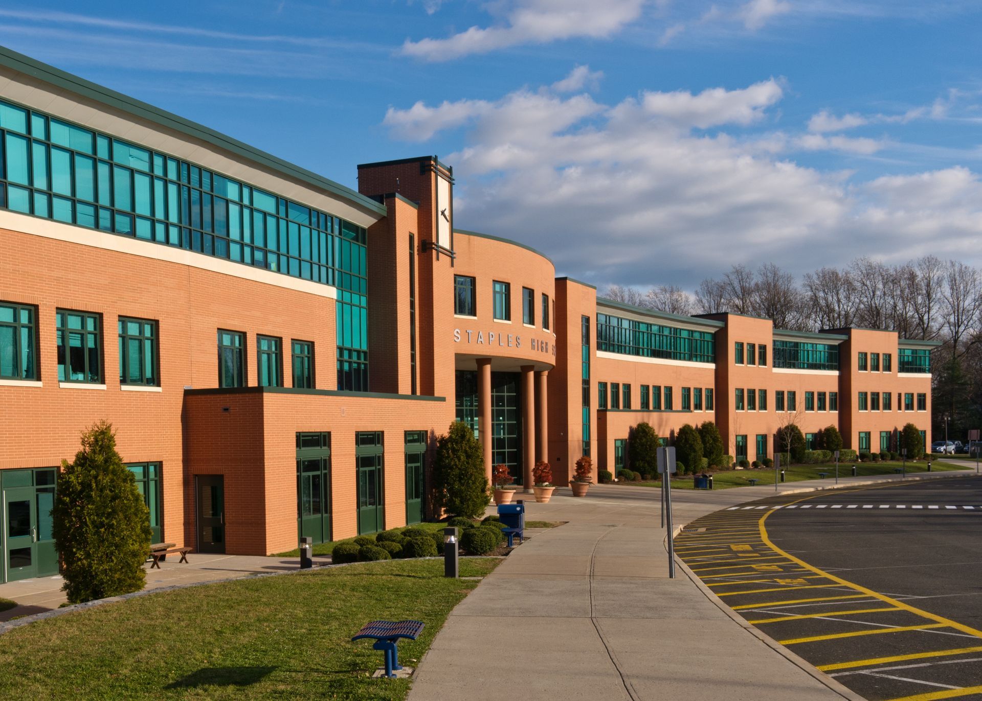 Modern brick school building with blue windows and a sidewalk in front