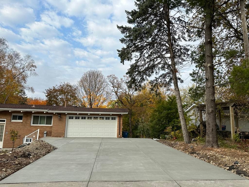 A brick house with a concrete driveway leading to it