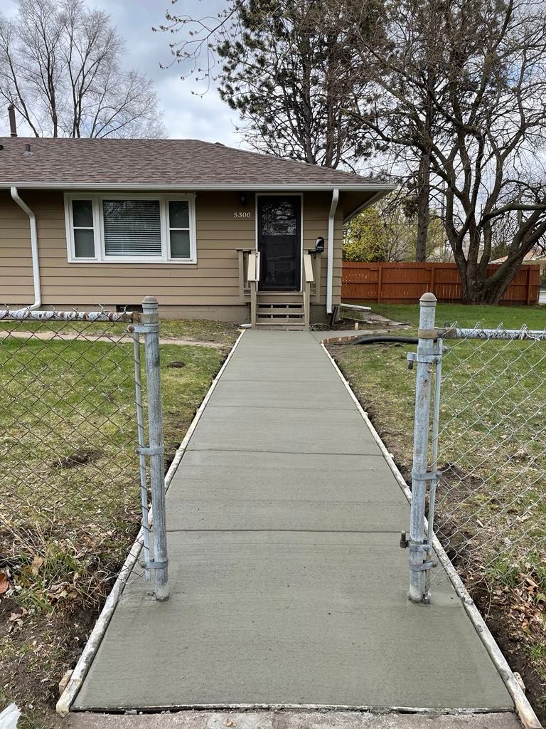 A concrete walkway leading to the front door of a house.