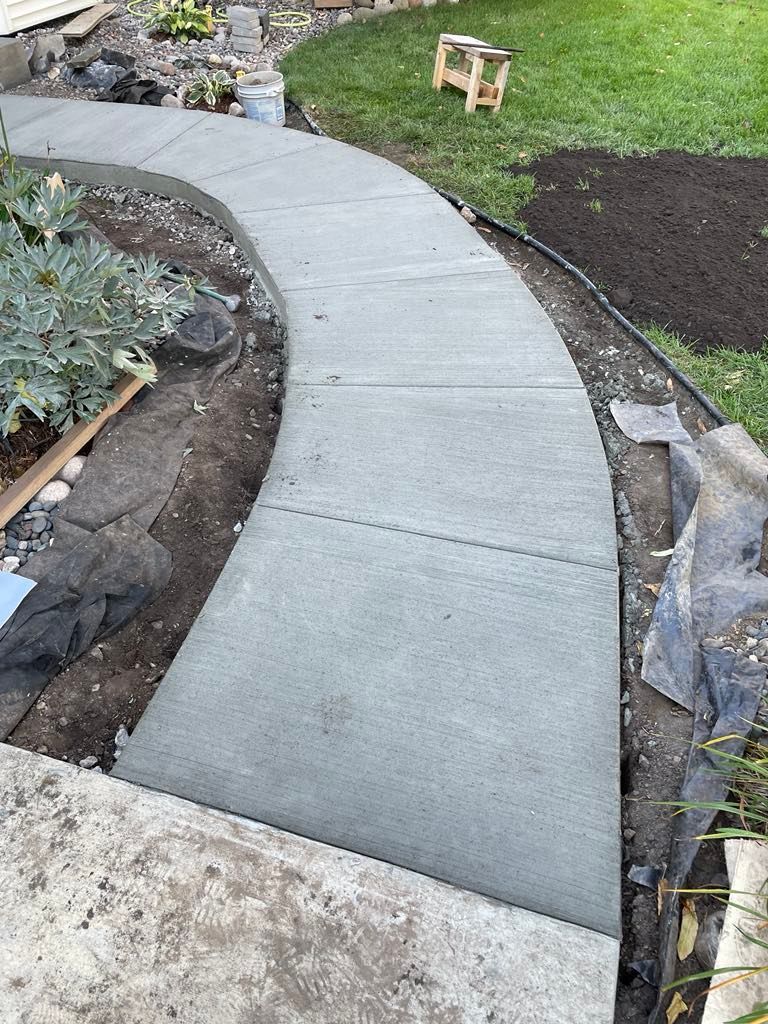 A concrete walkway is being built in a backyard.