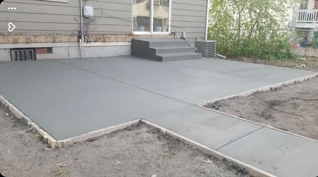 A concrete patio is being built in front of a house.