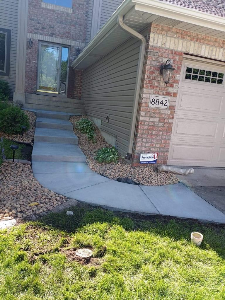 A concrete walkway leading to the front door of a house.
