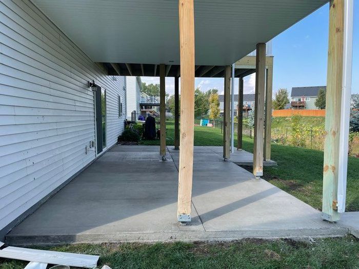 A concrete patio with a wooden deck underneath it