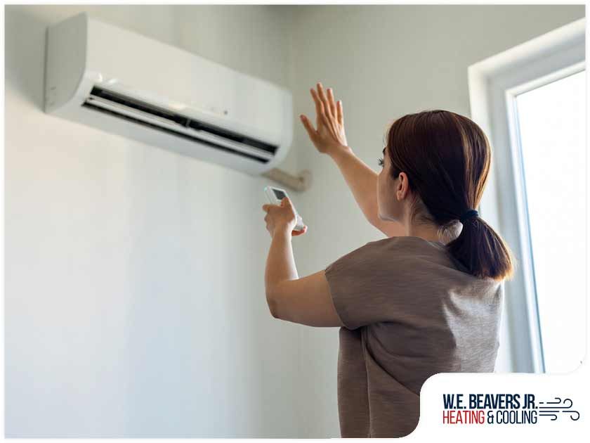 A woman is adjusting her air conditioner with a remote control.