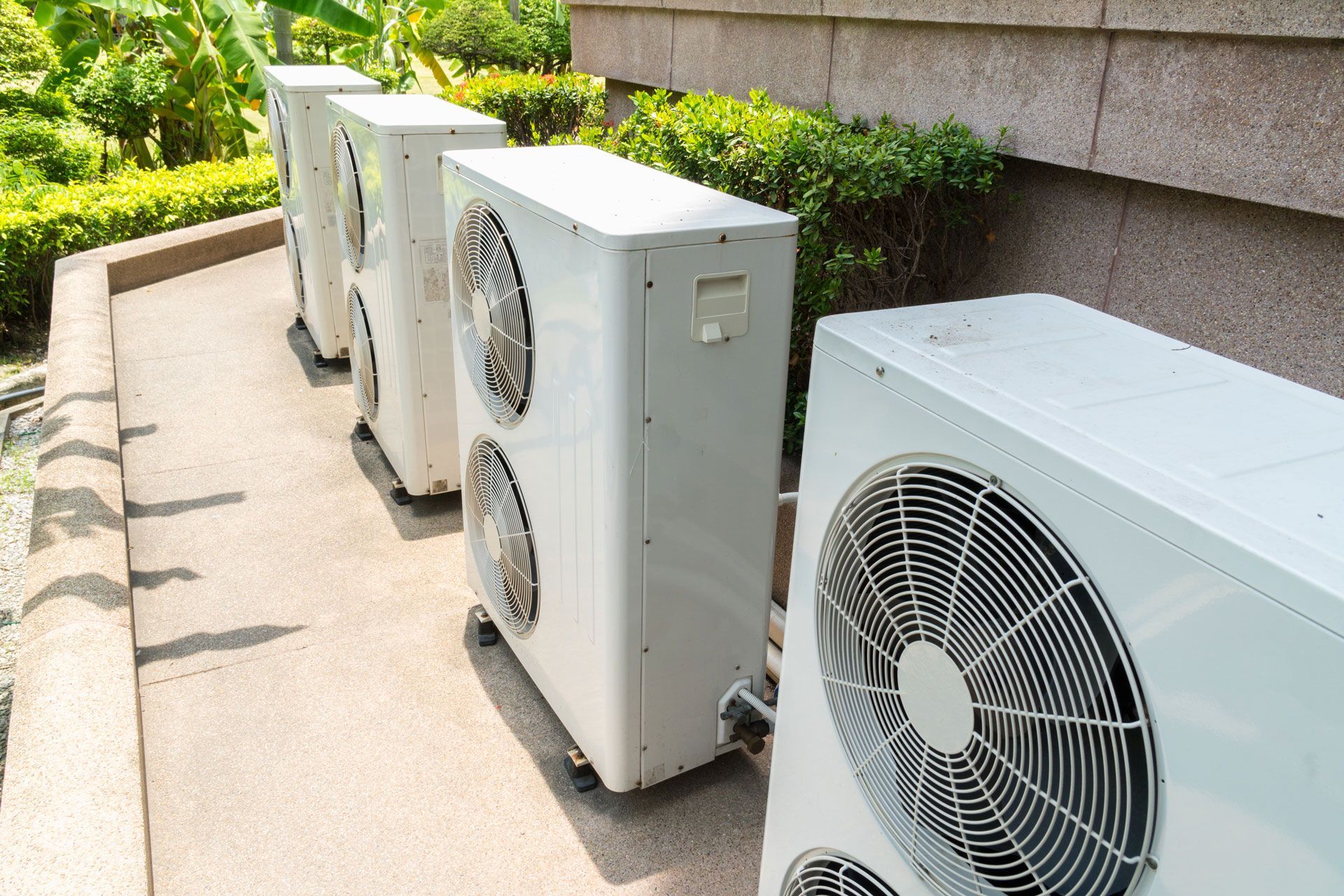A row of air conditioners are sitting outside of a building.