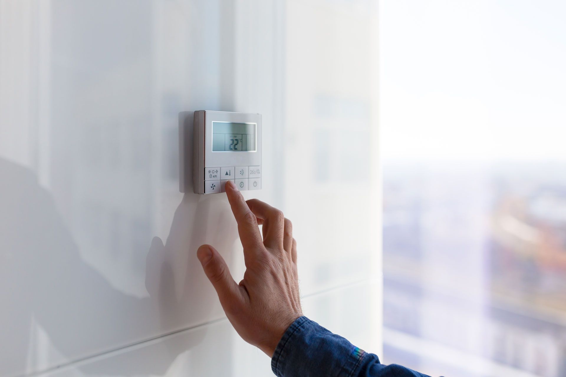 A person is adjusting a thermostat on a wall.