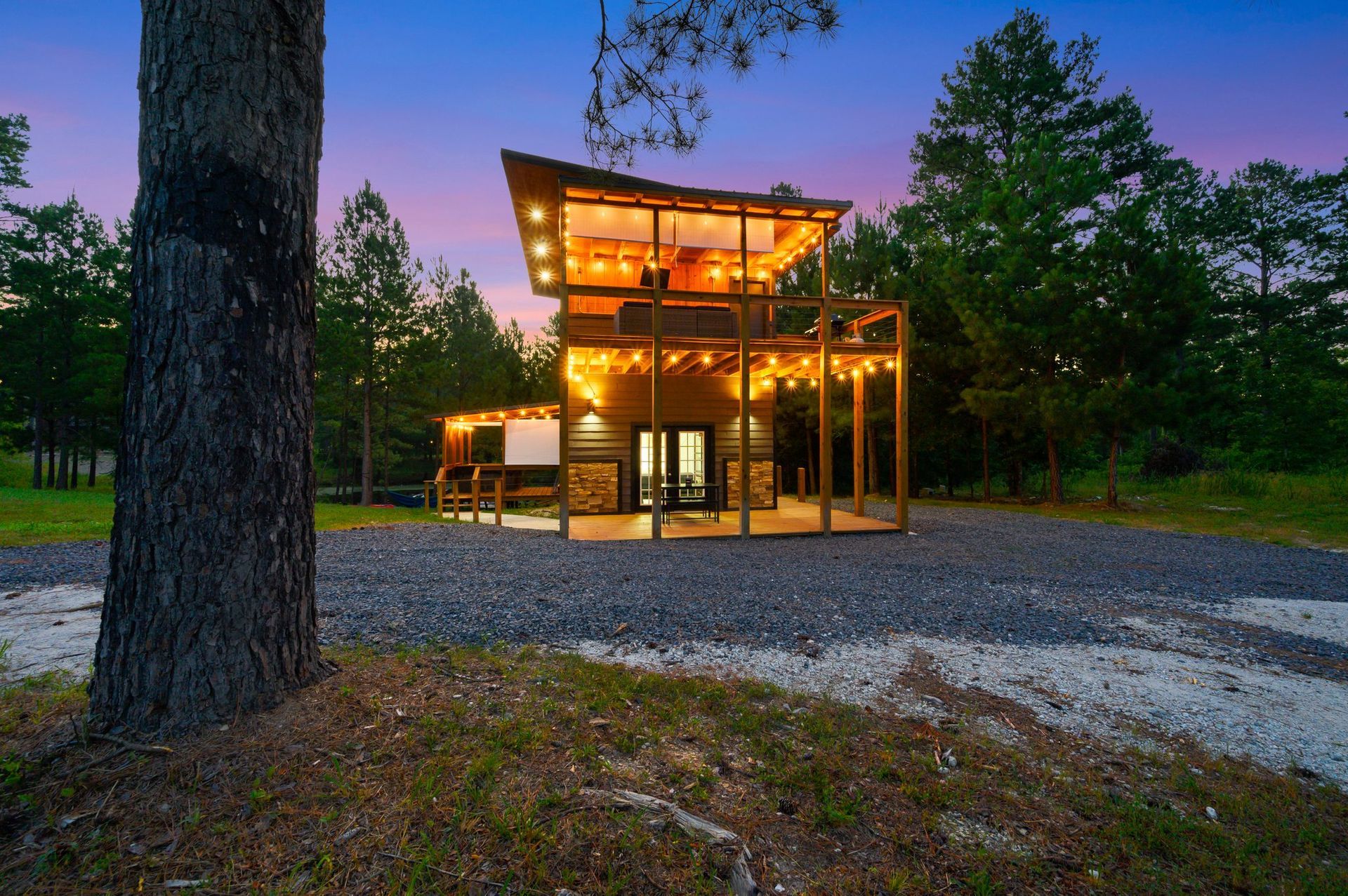 A small house is lit up at night in the middle of a forest.