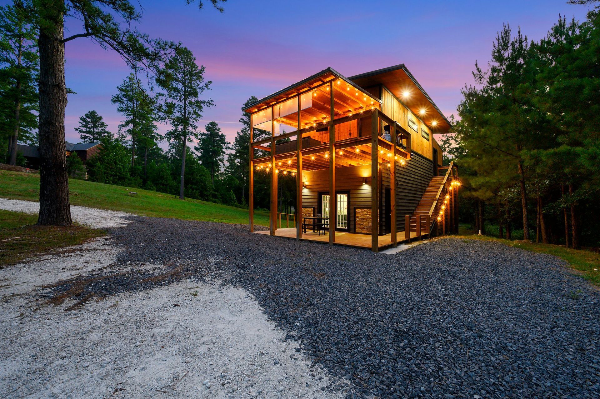 A large house is lit up at night in the middle of a forest.