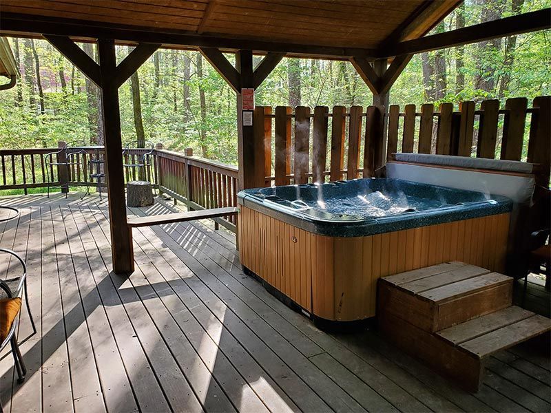 A hot tub is sitting on a wooden deck under a canopy.