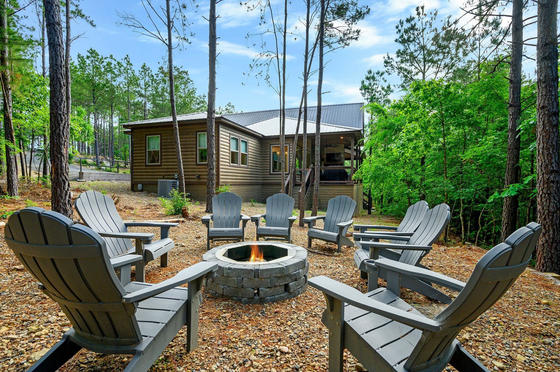 A spacious outdoor patio with blue wicker furniture, stone fireplace, and television on a wood cabin wall.