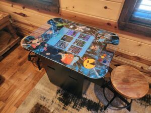 An arcade game is sitting on top of a wooden table in a room.