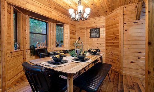 A dining room in a log cabin with a wooden table and chairs.