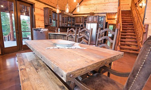 A wooden dining table and chairs in a log cabin.