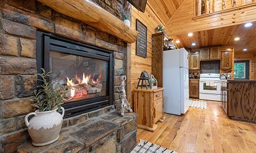 There is a fireplace in the middle of the room in a log cabin.