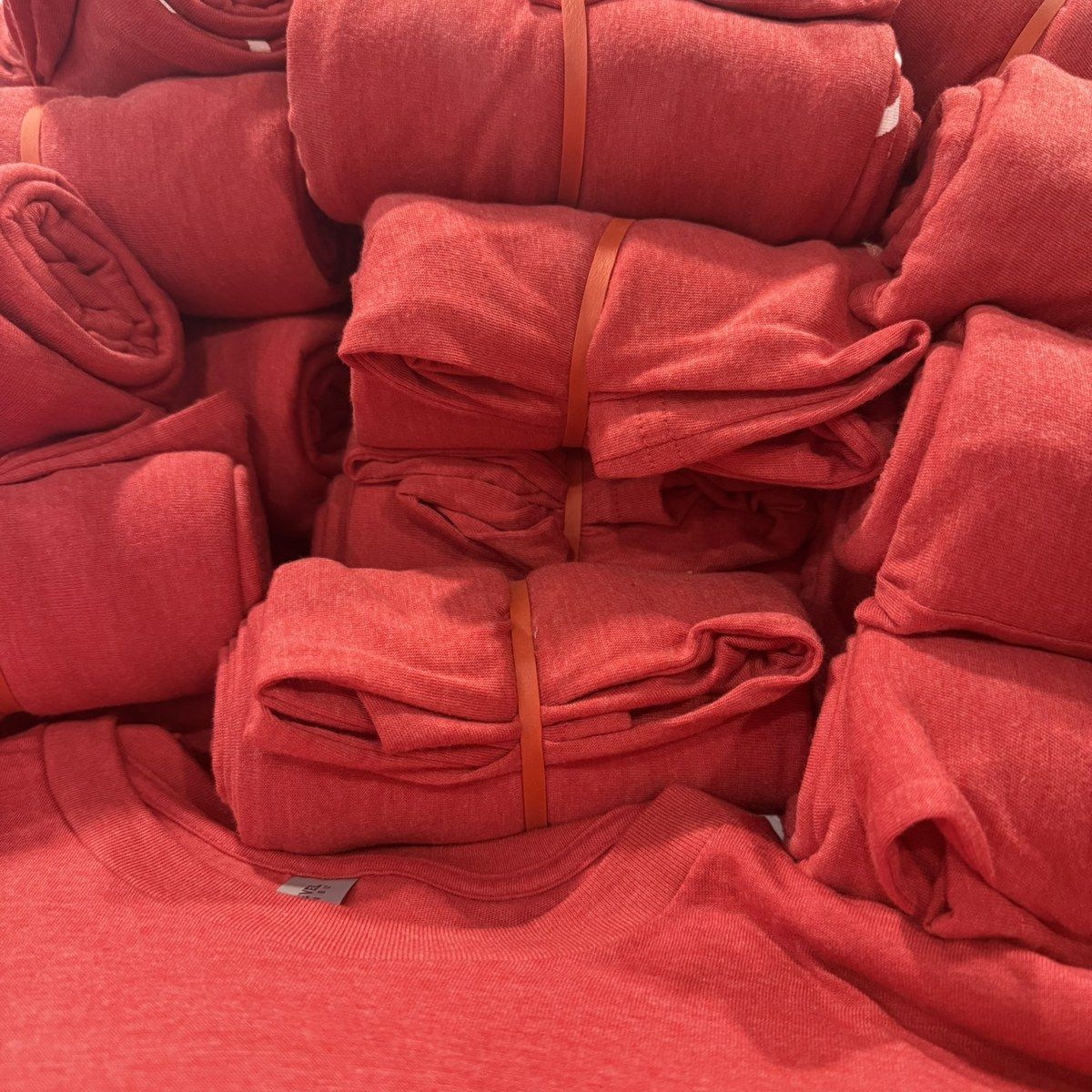 Stacks of freshly decorated red t-shirts bundled and ready to ship from a contract apparel decorator