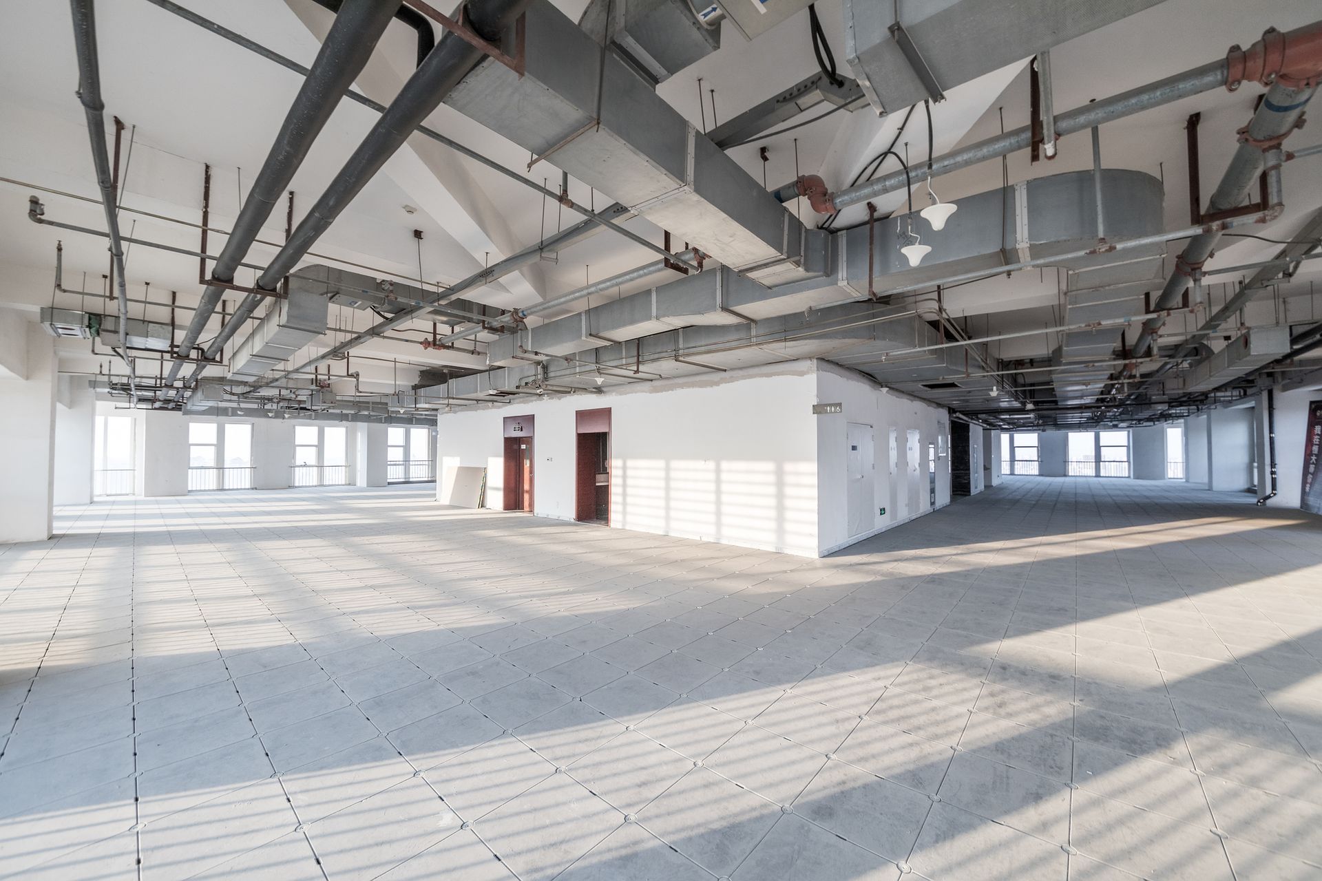 A large empty building with a lot of pipes hanging from the ceiling.