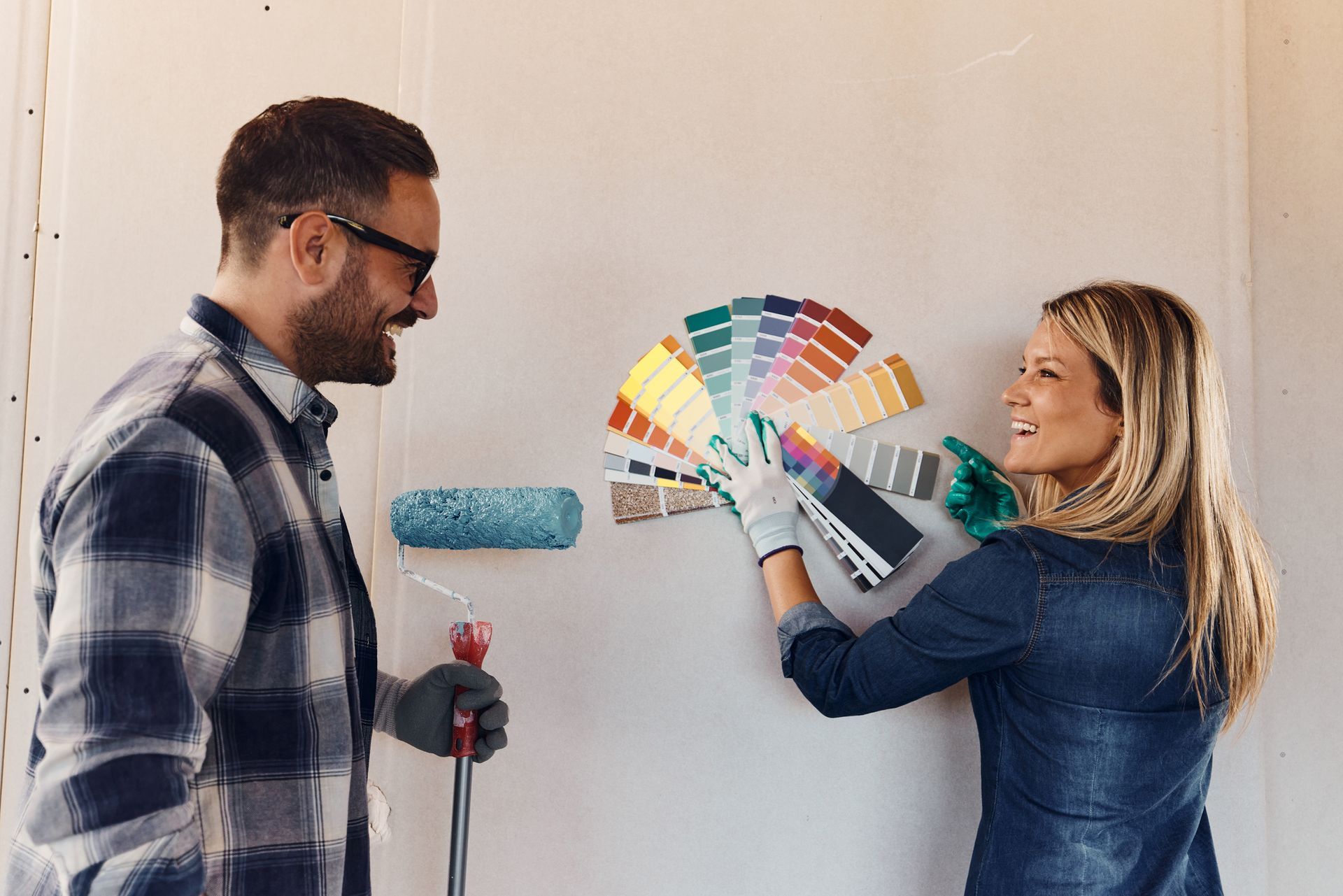 A man and a woman are looking at paint samples on a wall.