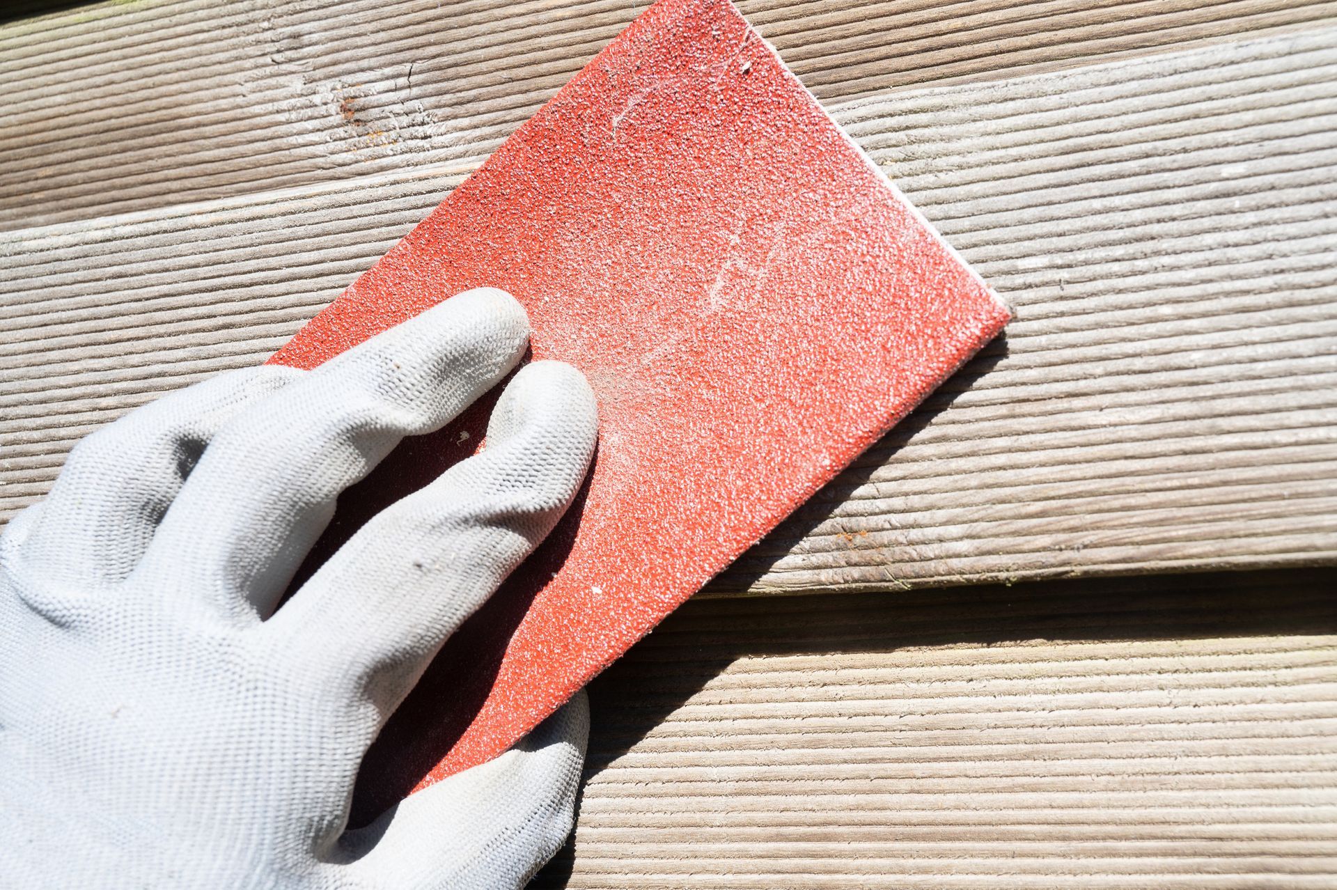 A person is sanding a piece of wood with a sandpaper.