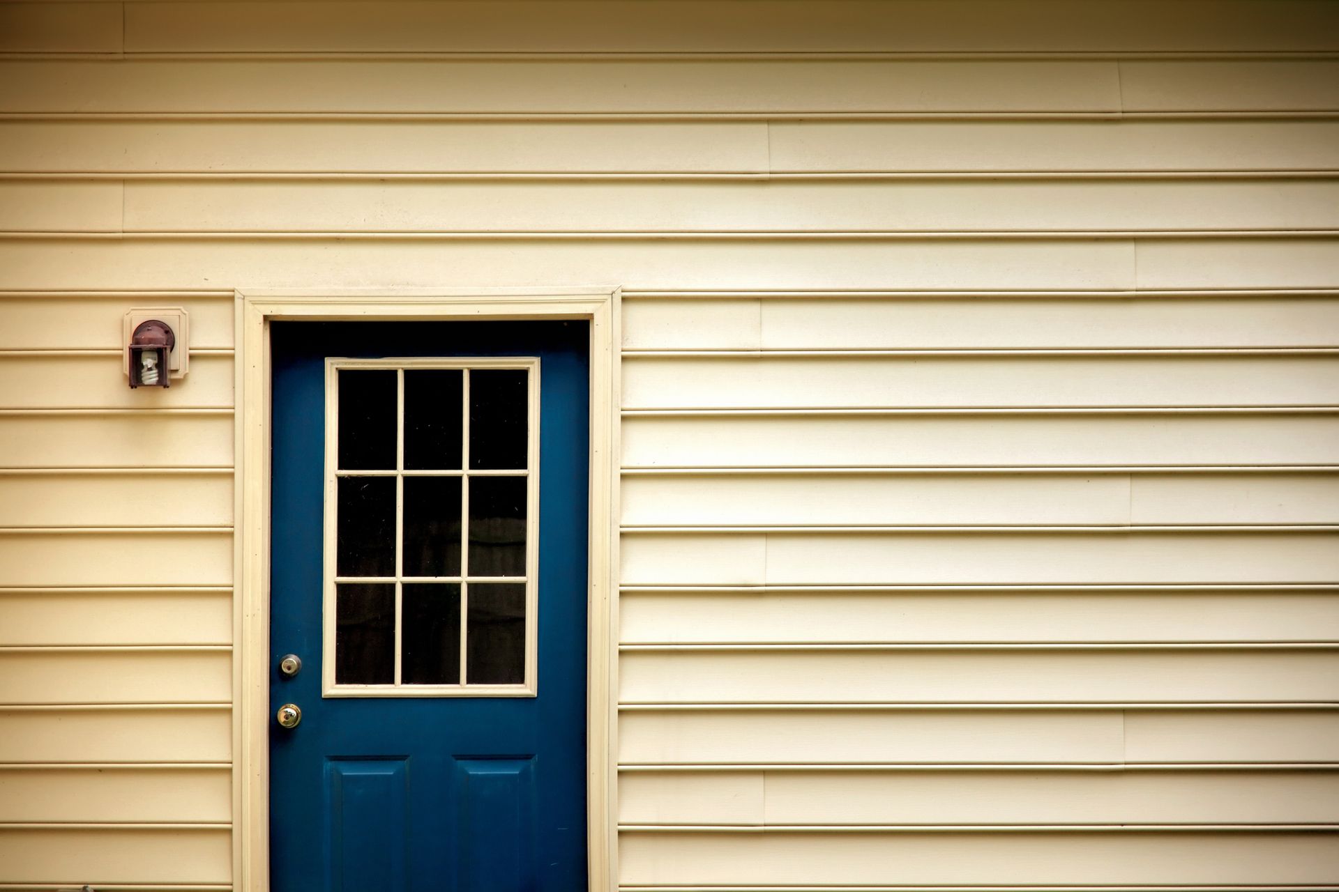 A blue door with a window on the side of a house.
