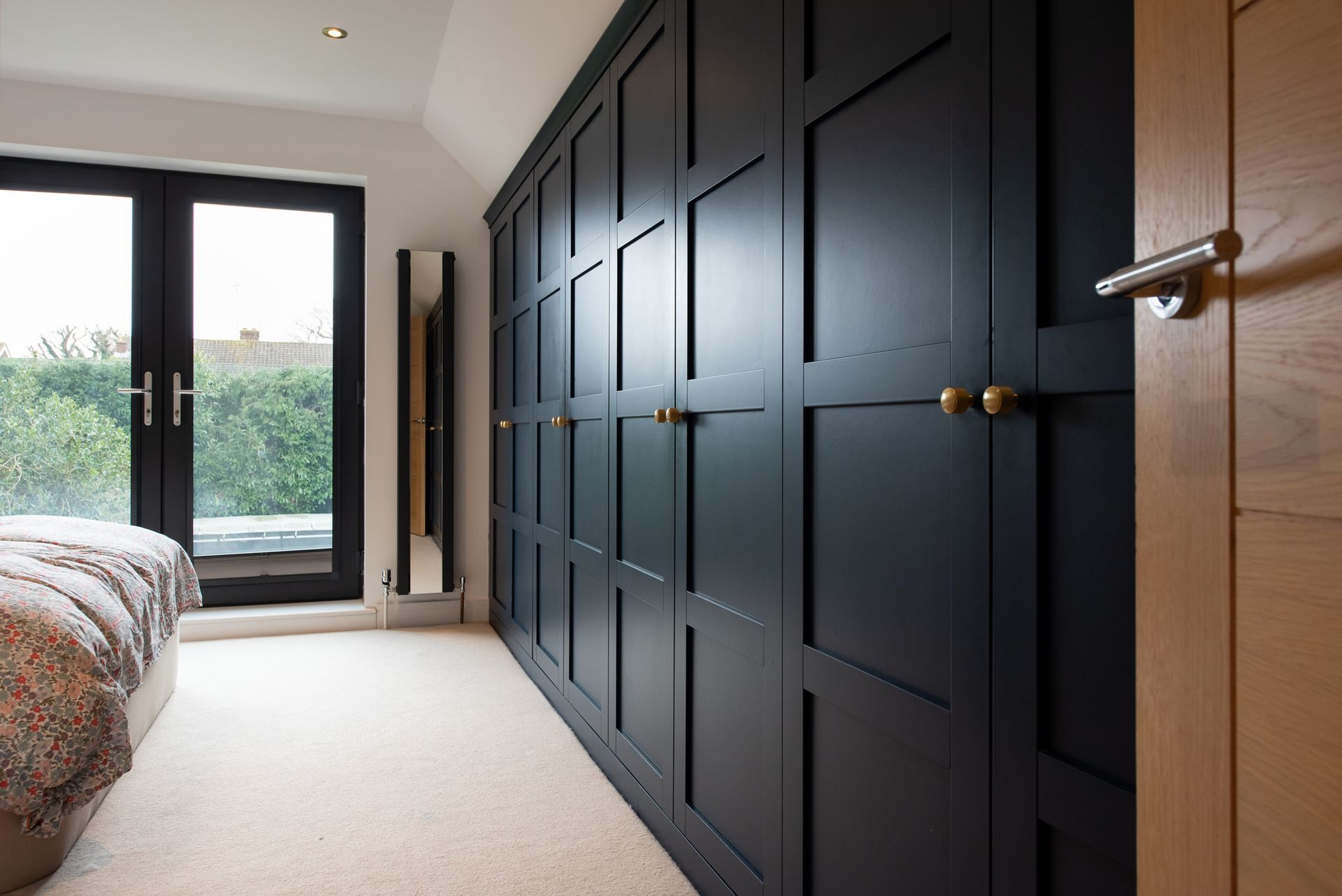 A bedroom with a bed , closets , and a large window.