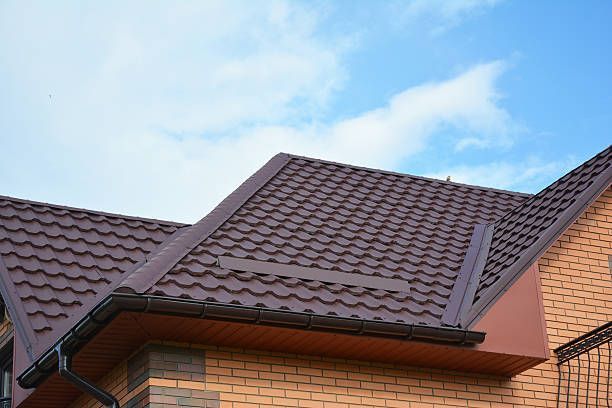 A brick house with a brown roof and a blue sky in the background.