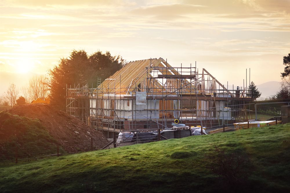 A house is being built on top of a grassy hill.