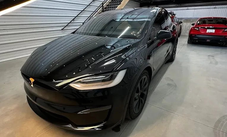 Black Mitsubishi sedan parked indoors with a red sports car in the background